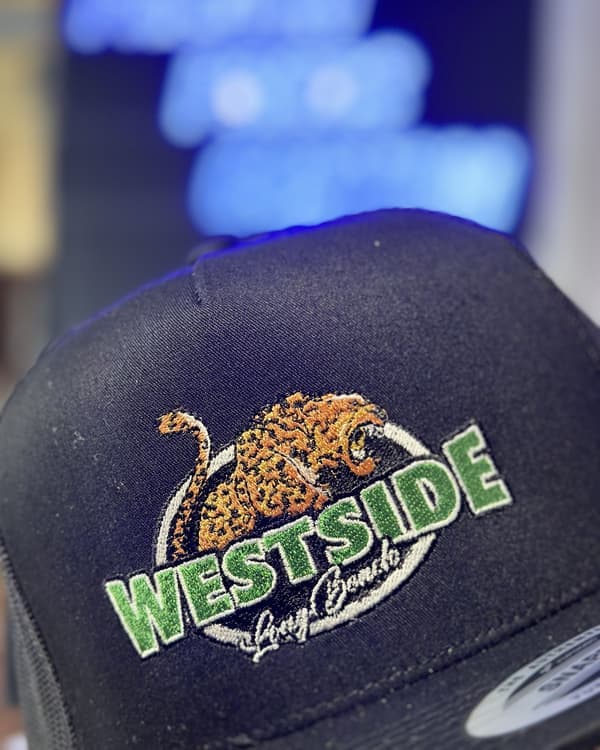 Multi-color leopard and varsity lettering embroidered on a black trucker hat